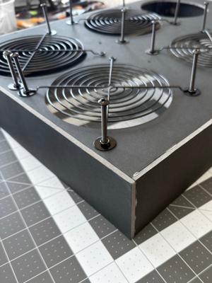 Installing the fan grills with washers correctly positioned underneath the fan grills on a rolling luggage style build.